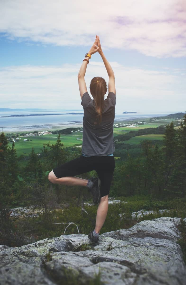 Photo by Sigmund woman standing on one leg on rock facing the field