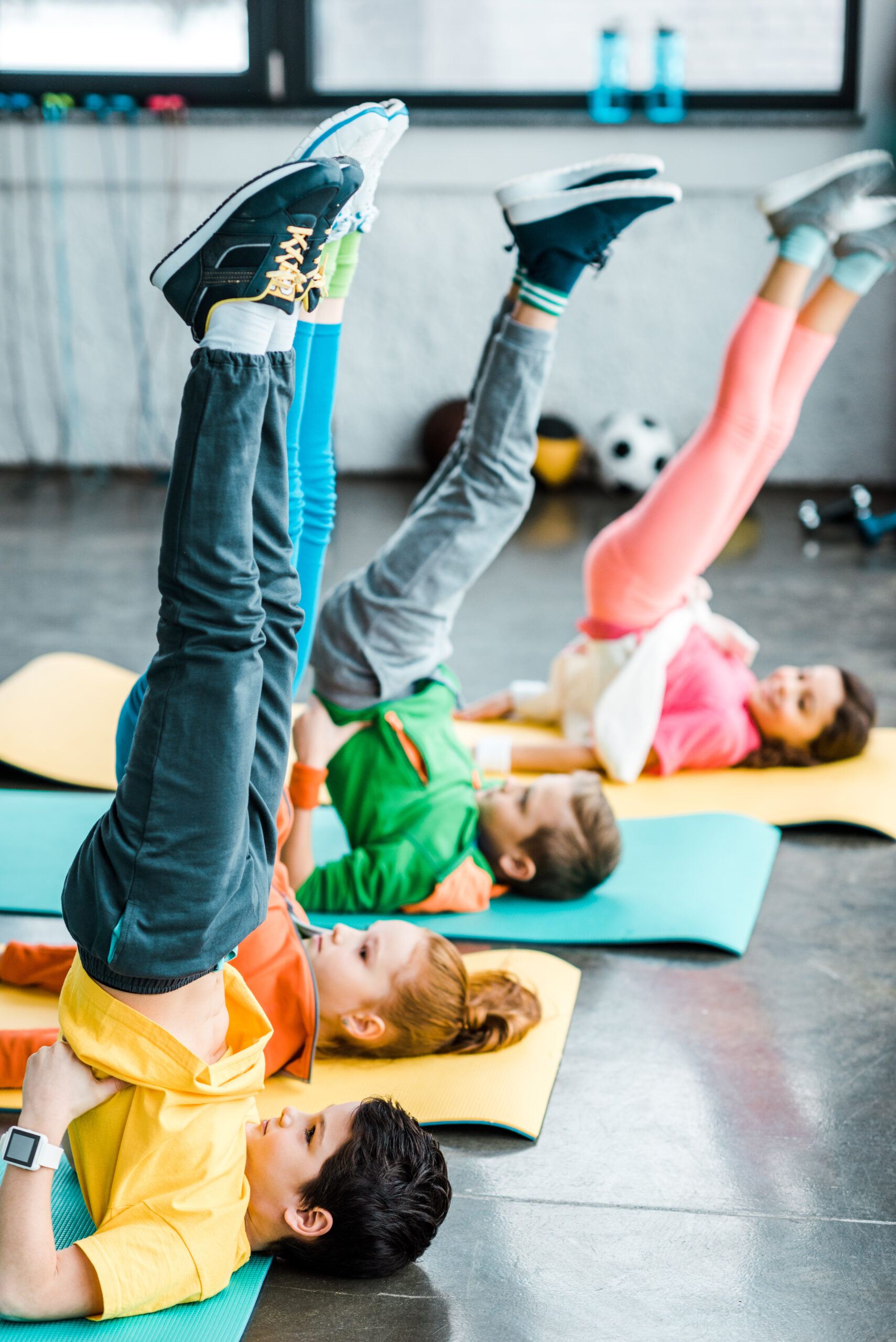 Kids doing candlestick exercise on mats in gym pourquoi une formation yoga pour enfants ?